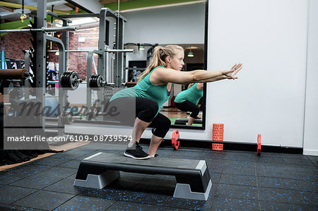 Pregnant woman performing stretching exercise in gym