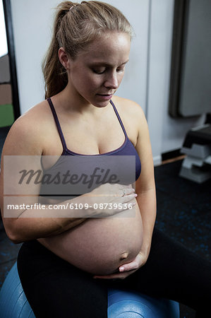Pregnant woman sitting on exercise ball in gym