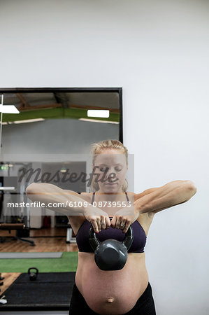 Pregnant woman lifting kettlebell in gym