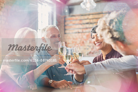 Friends toasting white wine glasses at restaurant table