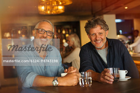 Portrait smiling men drinking coffee and water at restaurant table