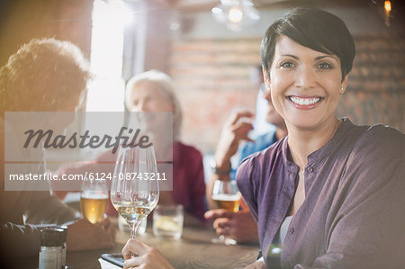 Portrait smiling woman drinking white wine dining with friends at restaurant table