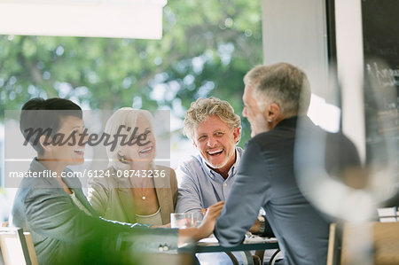 Smiling couples talking and dining at restaurant table