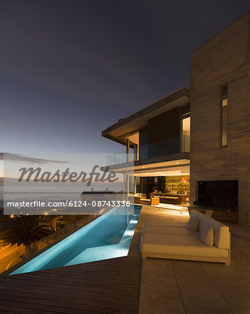 Illuminated home showcase exterior patio with lap pool and ocean view