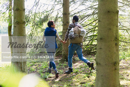 Couple holding hands and hiking with backpack in woods