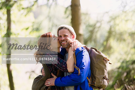Portrait smiling couple kissing hiking in woods