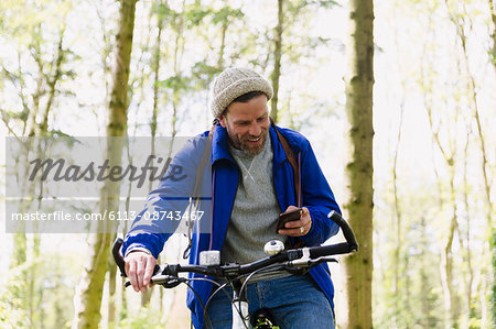 Man mountain biking texting with cell phone in woods