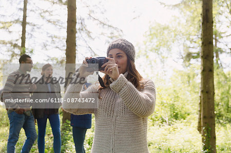 Woman using camera hiking in woods