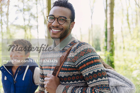 Portrait smiling man with backpack hiking in woods