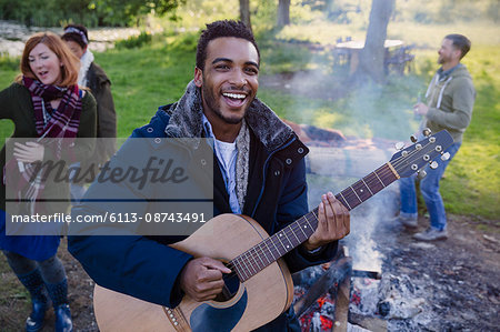 Portrait smiling man playing guitar with friends at campsite