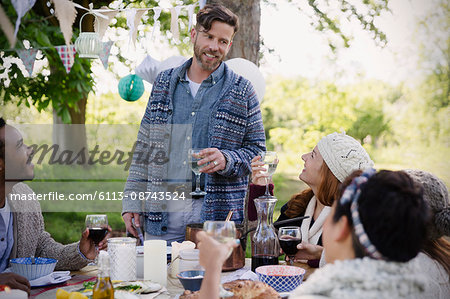 Man toasting friends at garden party table
