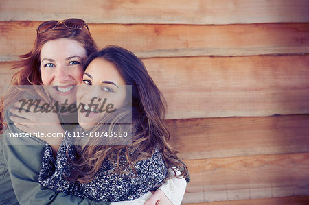 Portrait enthusiastic smiling female friends hugging outside cabin