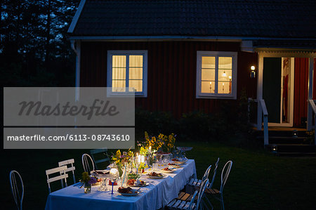 Candlelight garden party dinner outside illuminated house at night