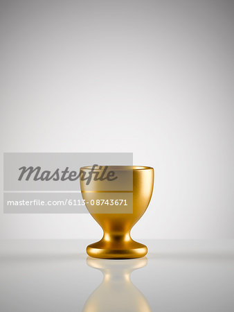 Empty golden egg cup holder against white background