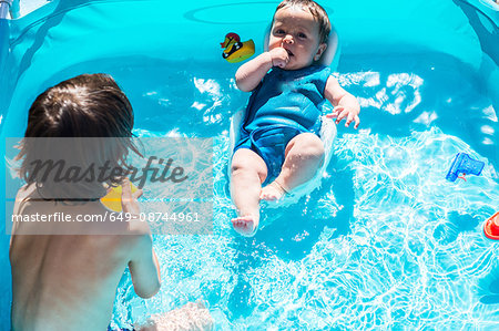 Happy brothers playing in inflatable pool on summer day