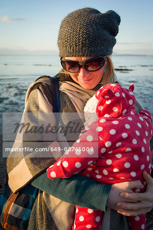 Mother by sea holding sleeping baby girl