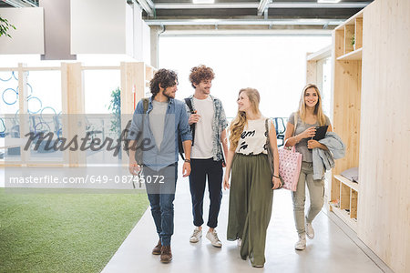 Co-workers walking along corridor in open plan office