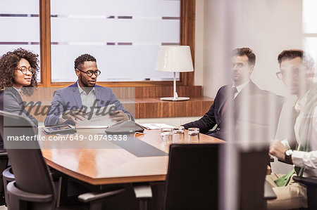 Businesswoman and men having discussion at boardroom table meeting