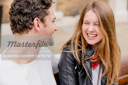 Happy young couple sitting on park bench