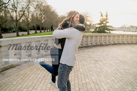 Romantic young man hugging girlfriend in Battersea Park, London, UK Romantic young man hugging girlfriend in Battersea Park, London, UK