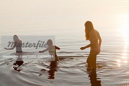 Girls wading in lake at sunset