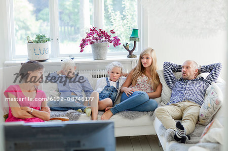 Family with three kids watching tv on sofa