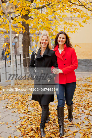 Two female friends walking together in park