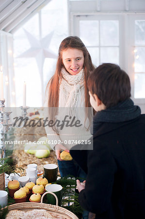 Girl and boy with apples in greenhouse