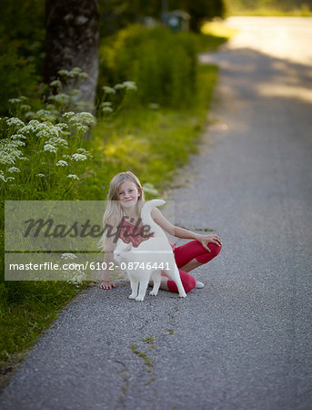 Smiling girl on road with white cat