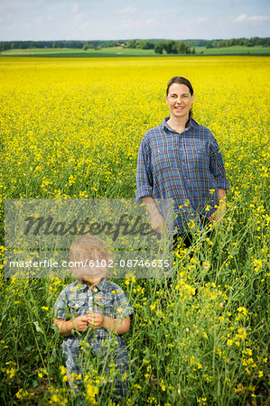 Smiling woman with girl on oilseed rape field