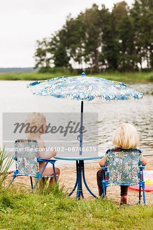 Little kids sitting on chair at beach