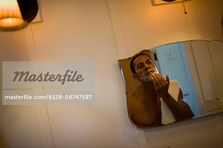 Young man preparing to shave his face in the bathroom mirror.