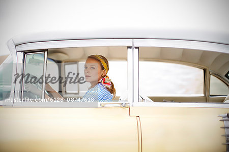 Young woman in 1950s outfit driving a vintage car