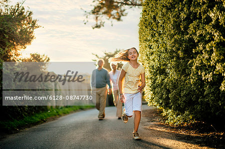 Mature couple walking with their young granddaughter.