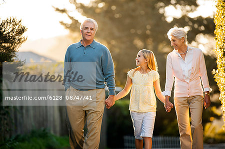 Mature couple walking hand in hand with their young granddaughter.