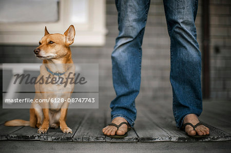 Man standing on his deck with his dog by his side.