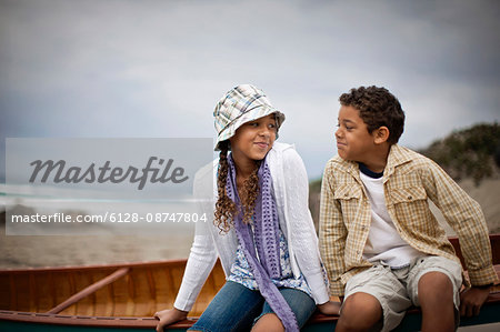 Young siblings sitting together at beach.