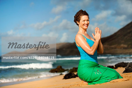 Portrait of a serene mid-adult woman practicing yoga on a beach.