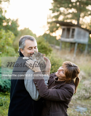 Mature couple embracing cat outdoors