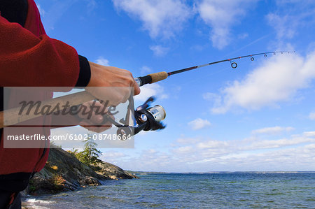 Woman holding fishing rod beside sea