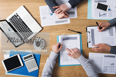 Business people team working together at office desk with laptop, tablet, financial paperwork and reports, top view