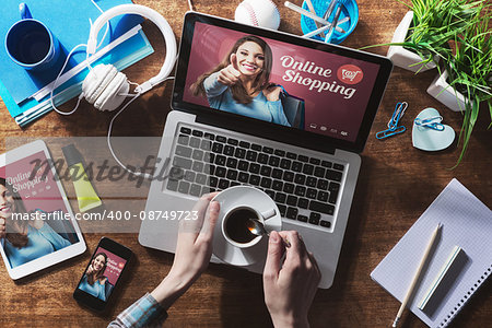 Online shopping website on laptop screen with female hands holding a coffee