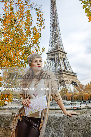 Autumn getaways in Paris. young elegant woman on embankment in Paris, France with map looking into the distance