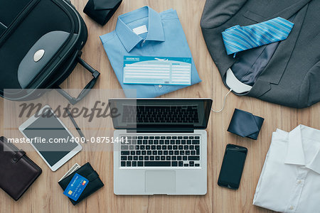 How to pack for a business trip: all items that needs to be packed, a bag and a laptop on a desktop, travel concept