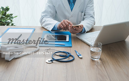 Professional doctor working at office desk, he is using a smartphone, healthcare and technology concept