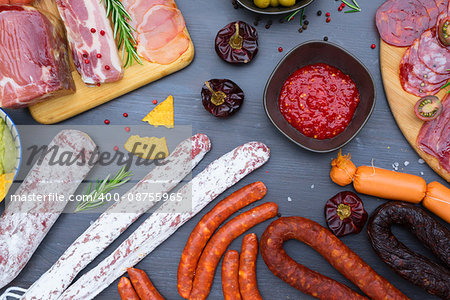 spanish tapas with salami, chorizo, lomo, jamon with red hol salsa sause and olives, picnic table, top view