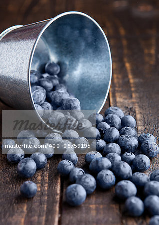 Blueberries in small steel bucket on grunge wooden board. Natural healthy food