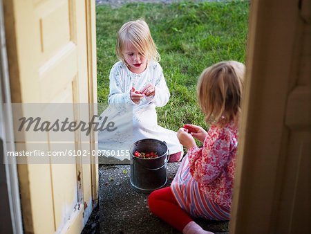 Girls eating strawberries outside house