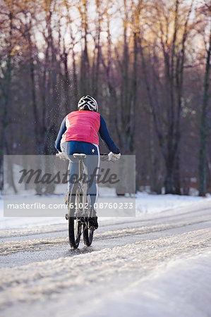 Mid adult woman cycling, rear view