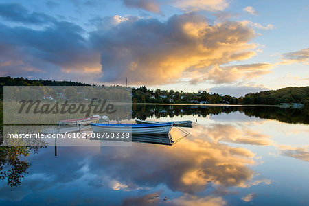 Rowboat floating on lake at sunset